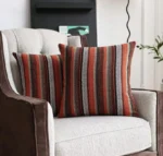 Deux housses de coussin rayées Rosewood sur un fauteuil beige et marron