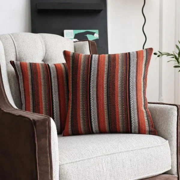Deux housses de coussin rayées Rosewood sur un fauteuil beige et marron