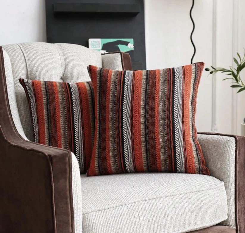 Deux housses de coussin rayées Rosewood sur un fauteuil beige et marron