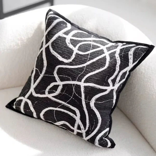Housse de coussin noire et blanche Thunder avec motif abstrait, idéale comme coussin décoratif moderne sur un canapé blanc.