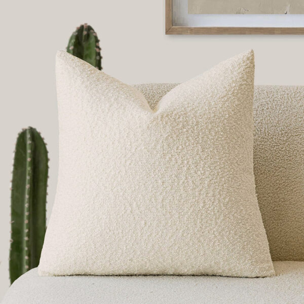 Housse de coussin bouclé blanc cassé sur canapé clair, coussin décoratif texturé doux