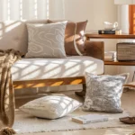 Housse de coussin design "Mocha" - Coussin marron chocolat avec motif ondulé blanc sur canapé beige.