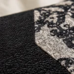 Détail texture coussin baroque noir et beige, broderie fine