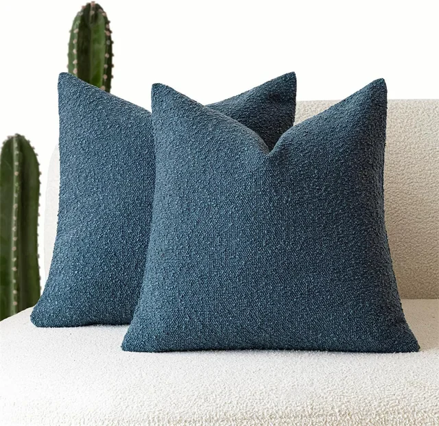 Deux housses de coussin bouclé bleu pétrole sur un canapé blanc, coussins décoratifs texturés pour ambiance raffinée