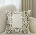 Housse de coussin brodée motif feuilles vertes et oiseaux sur fond crème.